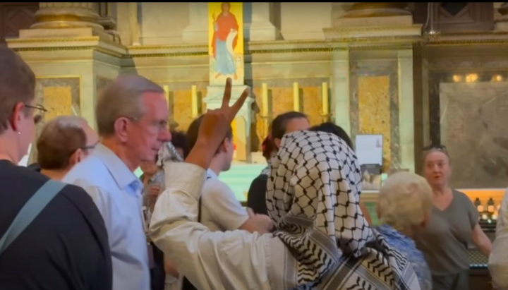 Пропалестинская активистка в церкви святой Мадлен во время акции, прервавшей мессу в Париже. Фото: скриншот Youtube
