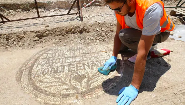 Археолог очищает мозаичную надпись у входа в христианскую церковь V века. Фото: foxnews